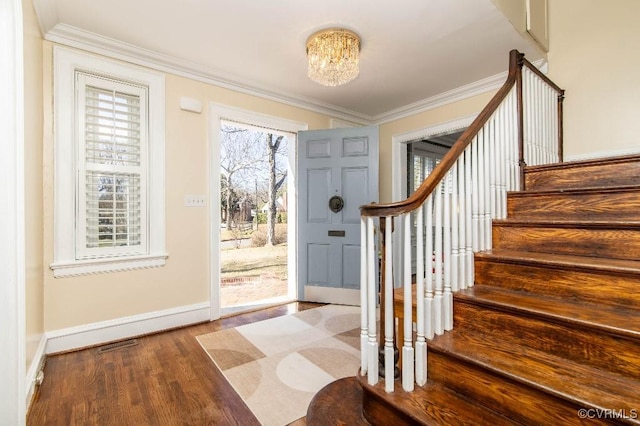 entrance foyer with ornamental molding, wood-type flooring, and an inviting chandelier