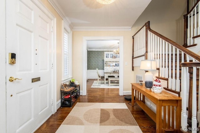 entrance foyer with a notable chandelier, crown molding, and dark wood-type flooring