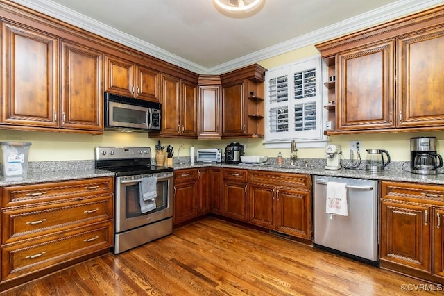 kitchen featuring sink, hardwood / wood-style flooring, stainless steel appliances, and stone counters