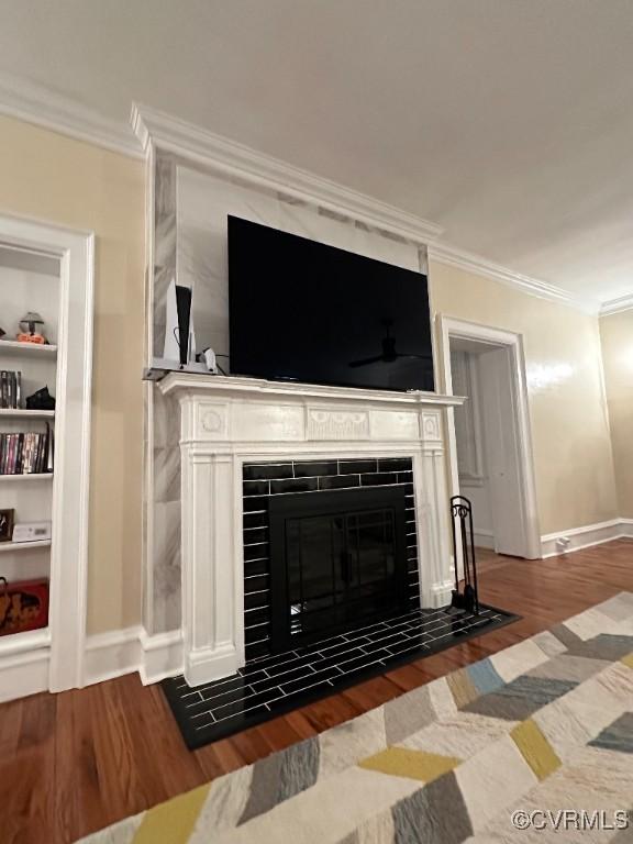 details featuring crown molding, a fireplace, built in shelves, and hardwood / wood-style flooring