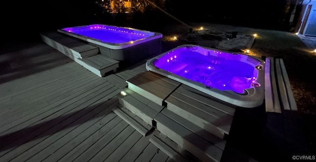 pool at twilight featuring an outdoor hot tub