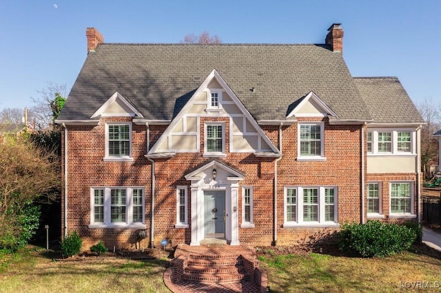 tudor home with brick siding and a chimney