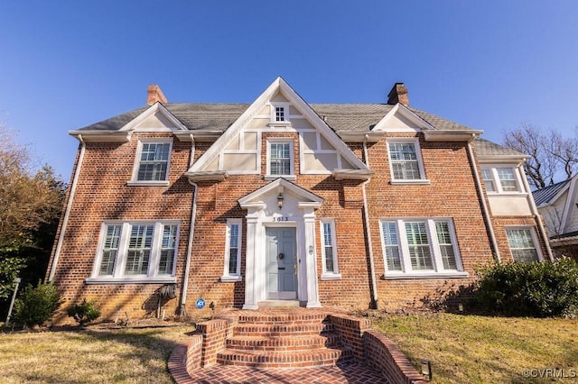 view of front of home with a chimney, a front lawn, and brick siding