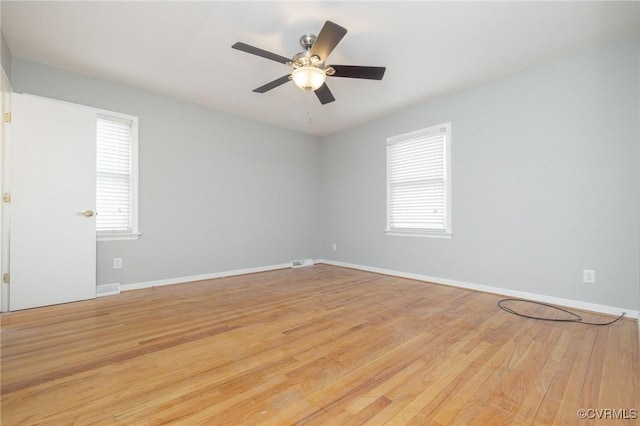 empty room with plenty of natural light, light wood-style flooring, baseboards, and ceiling fan