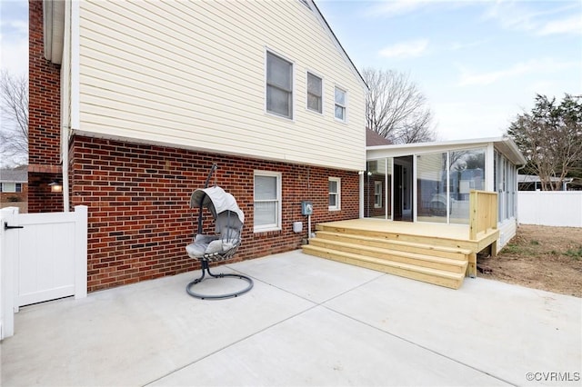 back of house with a patio, brick siding, fence, and a sunroom