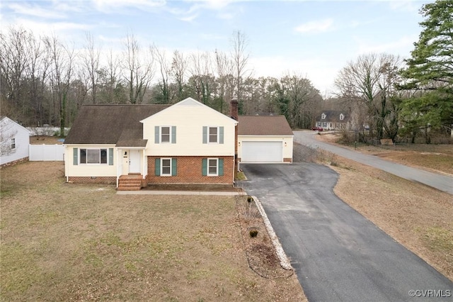 tri-level home featuring brick siding, a chimney, fence, a garage, and driveway