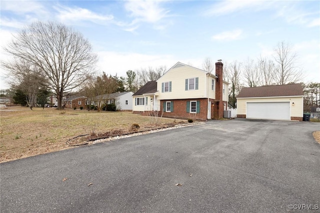 view of front of house with an outbuilding, central air condition unit, a garage, brick siding, and a chimney