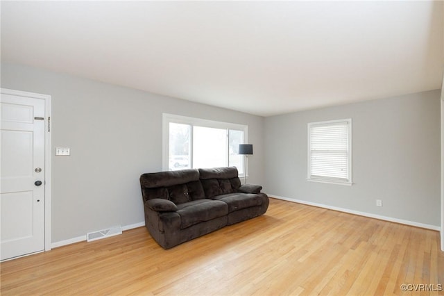 living room featuring visible vents, baseboards, and wood finished floors