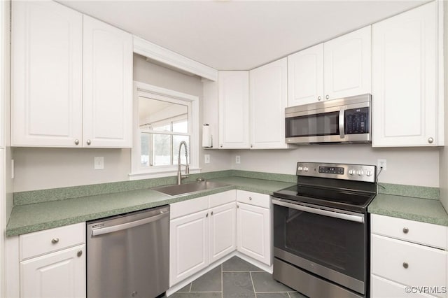 kitchen with appliances with stainless steel finishes, white cabinetry, and a sink