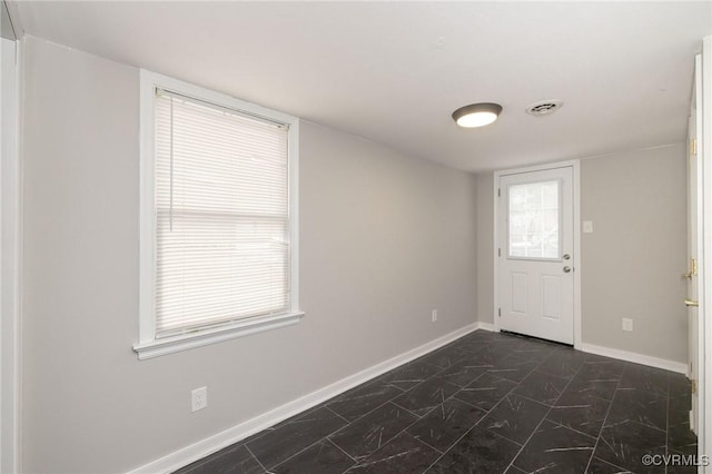 empty room with marble finish floor, visible vents, and baseboards