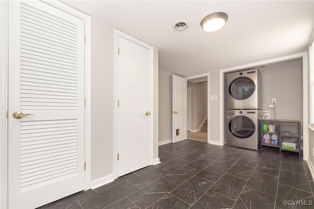 laundry room featuring laundry area, baseboards, visible vents, stacked washer / dryer, and marble finish floor