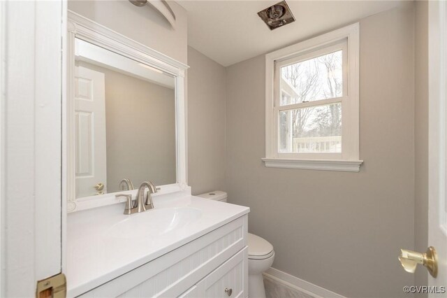 bathroom with toilet, baseboards, and vanity