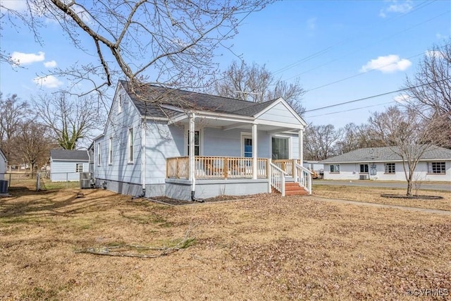 view of front of house with a front lawn, cooling unit, covered porch, and roof with shingles