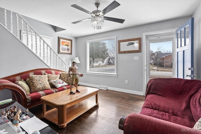 living area featuring dark wood-type flooring, a ceiling fan, visible vents, baseboards, and stairway