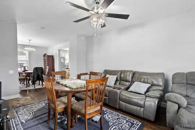 dining space with baseboards, dark wood-style flooring, and ceiling fan with notable chandelier