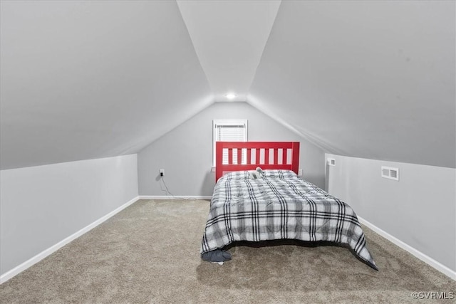 unfurnished bedroom with carpet floors, visible vents, vaulted ceiling, and baseboards