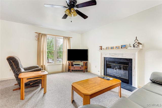 living area with a ceiling fan, a high end fireplace, light colored carpet, and baseboards