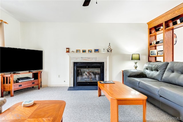 living room featuring a premium fireplace, carpet flooring, a ceiling fan, and baseboards