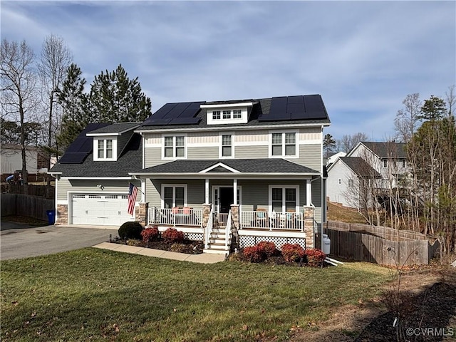 american foursquare style home featuring roof mounted solar panels, a porch, and a front yard