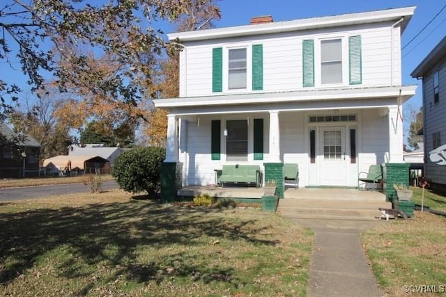 traditional style home with a front lawn, covered porch, and a chimney