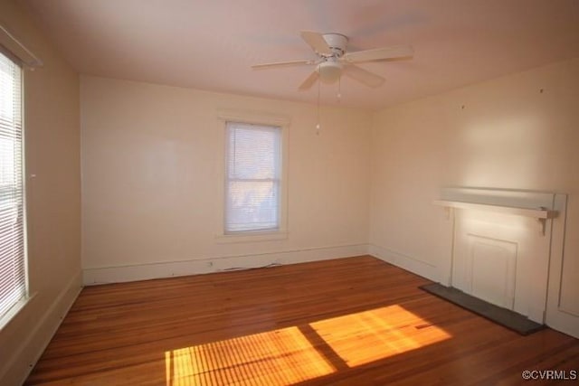 spare room with a ceiling fan, wood finished floors, and baseboards