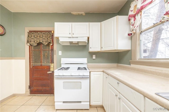 kitchen with white gas range, light tile patterned floors, and white cabinets