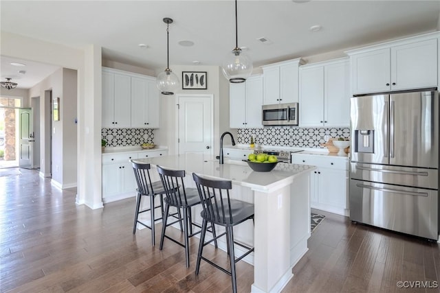 kitchen featuring white cabinetry, decorative light fixtures, dark hardwood / wood-style flooring, an island with sink, and stainless steel appliances