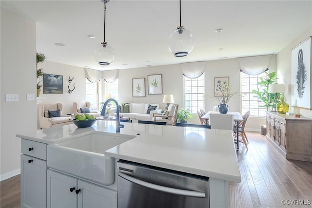 kitchen featuring white cabinetry, sink, decorative light fixtures, and stainless steel dishwasher