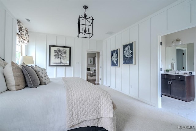 bedroom with ensuite bath, light carpet, and a notable chandelier