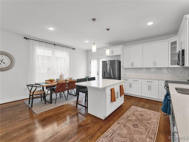 kitchen featuring pendant lighting, white cabinets, dark hardwood / wood-style flooring, a center island, and stainless steel appliances