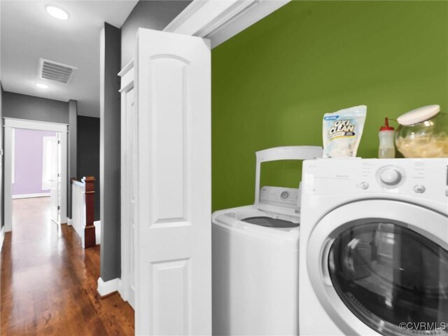 clothes washing area with dark wood-type flooring and washer and clothes dryer