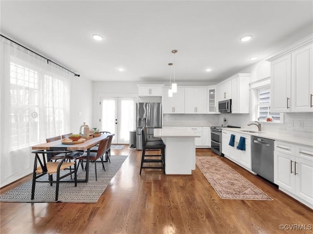 kitchen featuring pendant lighting, white cabinetry, a kitchen island, and appliances with stainless steel finishes