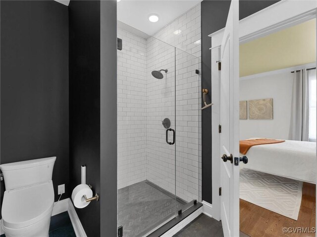 bathroom featuring hardwood / wood-style flooring, walk in shower, and toilet