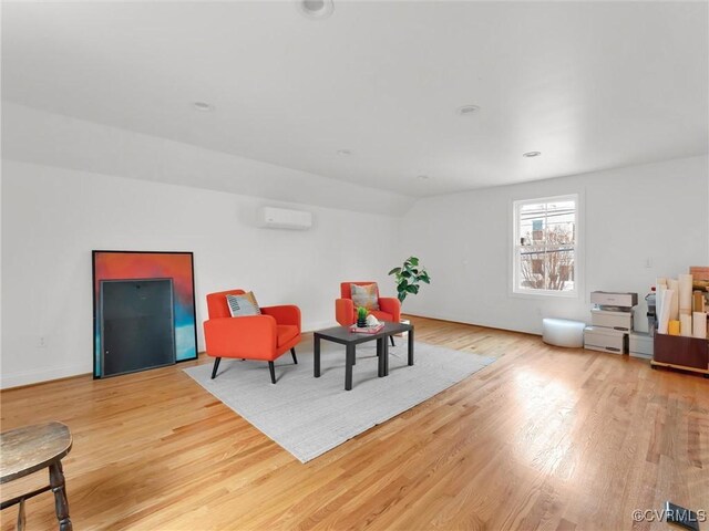 living area featuring a wall mounted air conditioner and light hardwood / wood-style floors