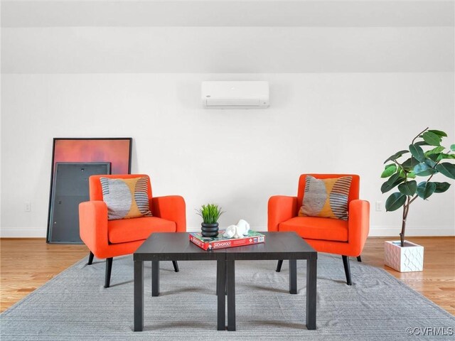 sitting room with hardwood / wood-style floors and a wall mounted AC