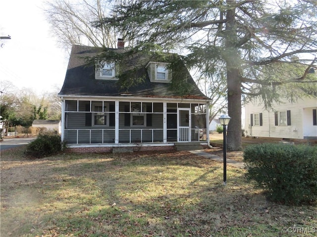 back of property with a sunroom and a lawn