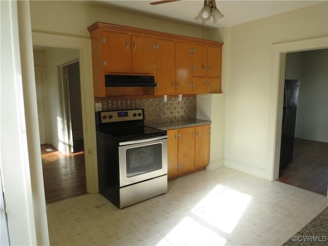 kitchen featuring tasteful backsplash, black refrigerator, ceiling fan, and stainless steel electric range