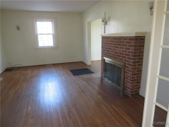 unfurnished living room featuring dark wood-type flooring and a brick fireplace