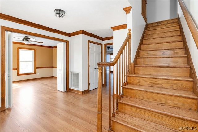 staircase featuring ceiling fan, ornamental molding, wood finished floors, and visible vents