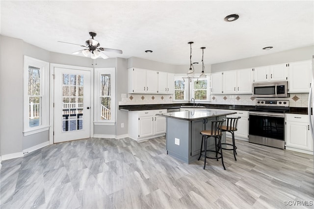 kitchen featuring appliances with stainless steel finishes, dark countertops, a kitchen island, and white cabinets