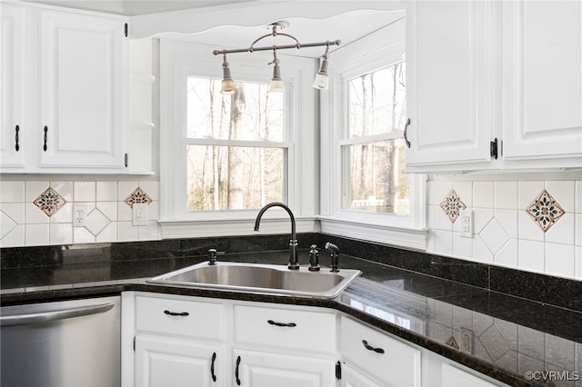 kitchen with hanging light fixtures, white cabinetry, a sink, dark stone countertops, and dishwasher