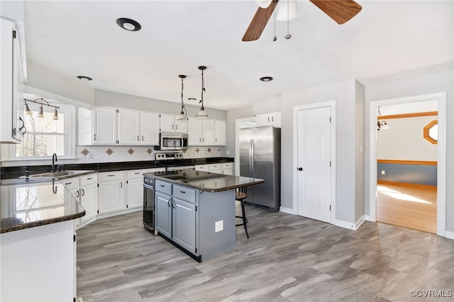 kitchen with white cabinets, appliances with stainless steel finishes, a kitchen breakfast bar, a center island, and a sink