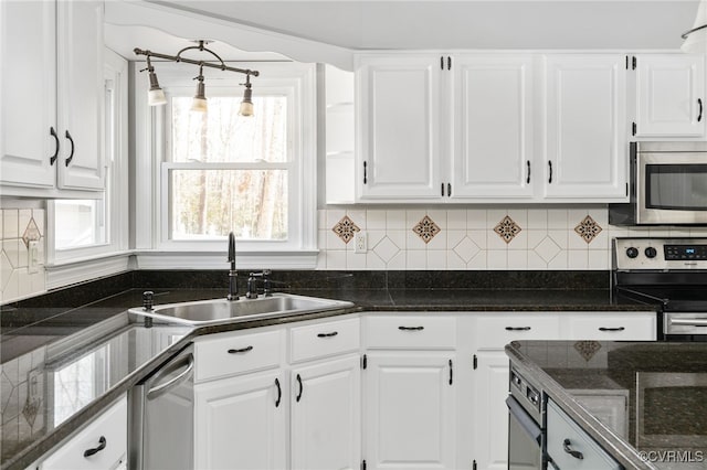 kitchen featuring appliances with stainless steel finishes, white cabinets, a sink, and decorative backsplash