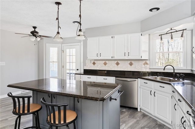 kitchen with a kitchen island, white cabinets, dishwasher, and a sink