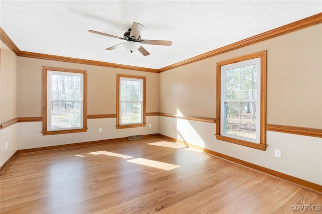 unfurnished room with light wood finished floors, a wealth of natural light, and baseboards