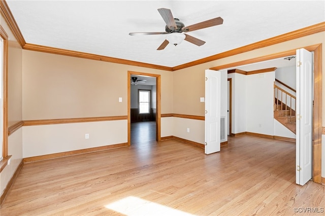 spare room featuring ornamental molding, light wood finished floors, stairway, and baseboards