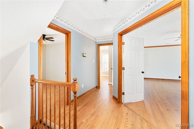 hall featuring baseboards, an upstairs landing, and light wood-style floors