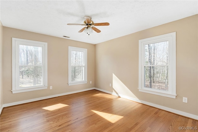 spare room featuring ceiling fan, light wood-type flooring, visible vents, and baseboards