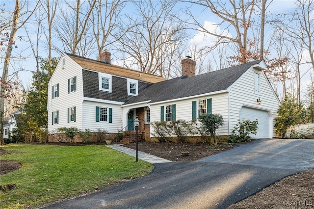 dutch colonial featuring a garage, driveway, roof with shingles, a front lawn, and a chimney