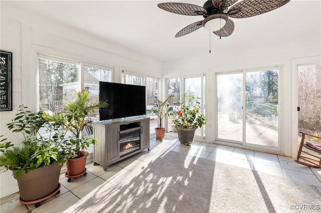 sunroom / solarium featuring a glass covered fireplace and a ceiling fan